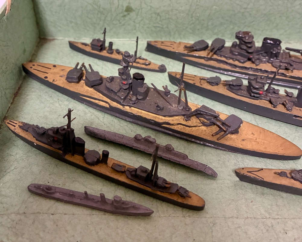 A vintage green cardboard box containing a set of miniature diecast metal model warships of the British Navy. View III