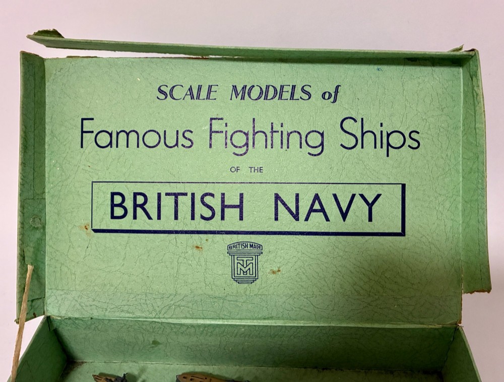 A vintage green cardboard box containing a set of miniature diecast metal model warships of the British Navy. View V