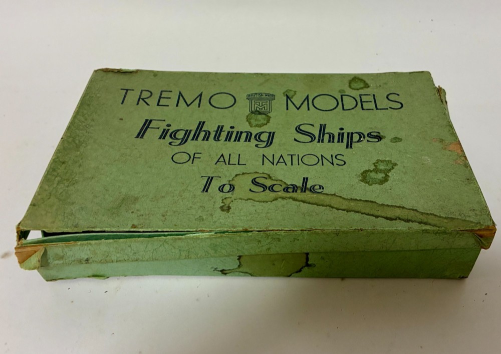 A vintage green cardboard box containing a set of miniature diecast metal model warships of the British Navy. View VI