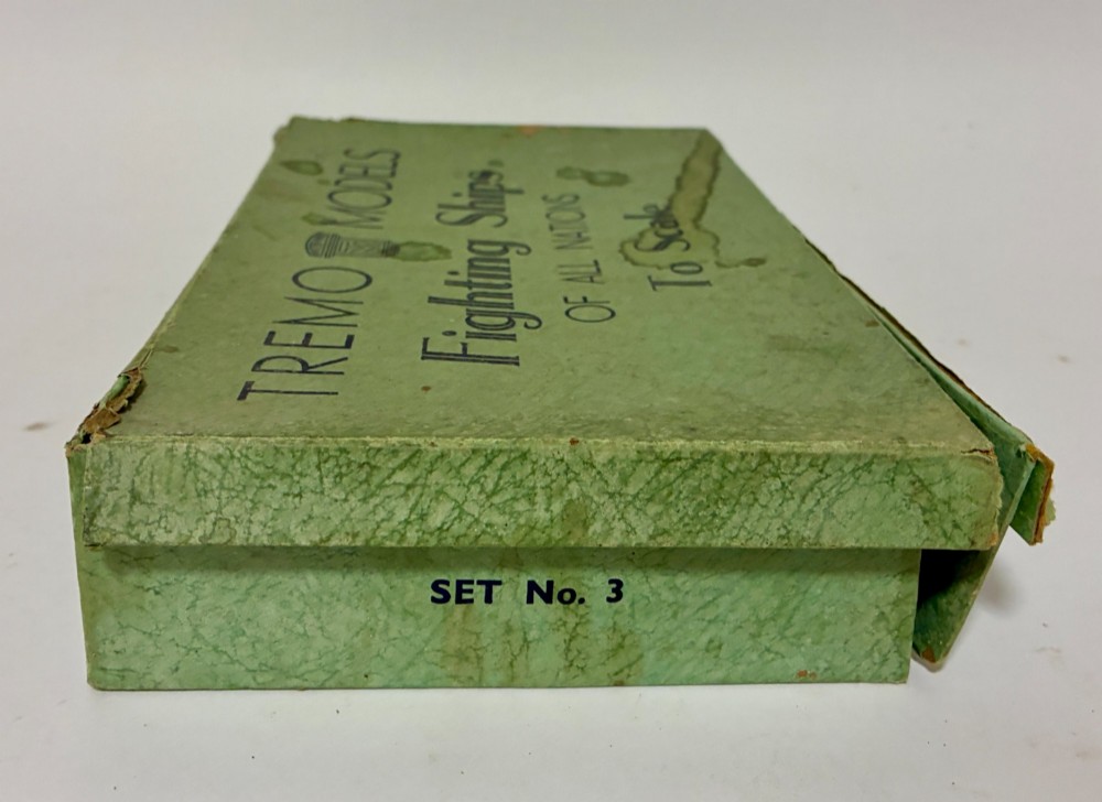 A vintage green cardboard box containing a set of miniature diecast metal model warships of the British Navy. View IX