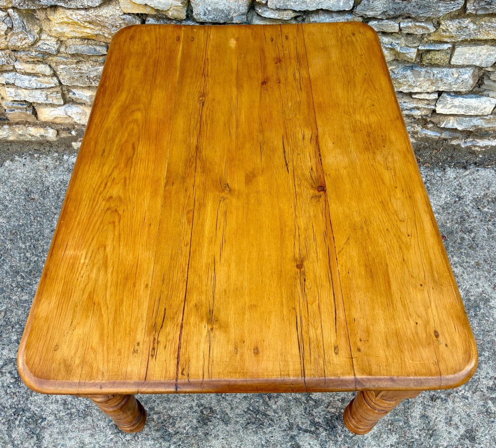 An antique pine farmhouse table featuring turned legs, a frieze drawer with a wooden knob, and a warm timber finish. View IV