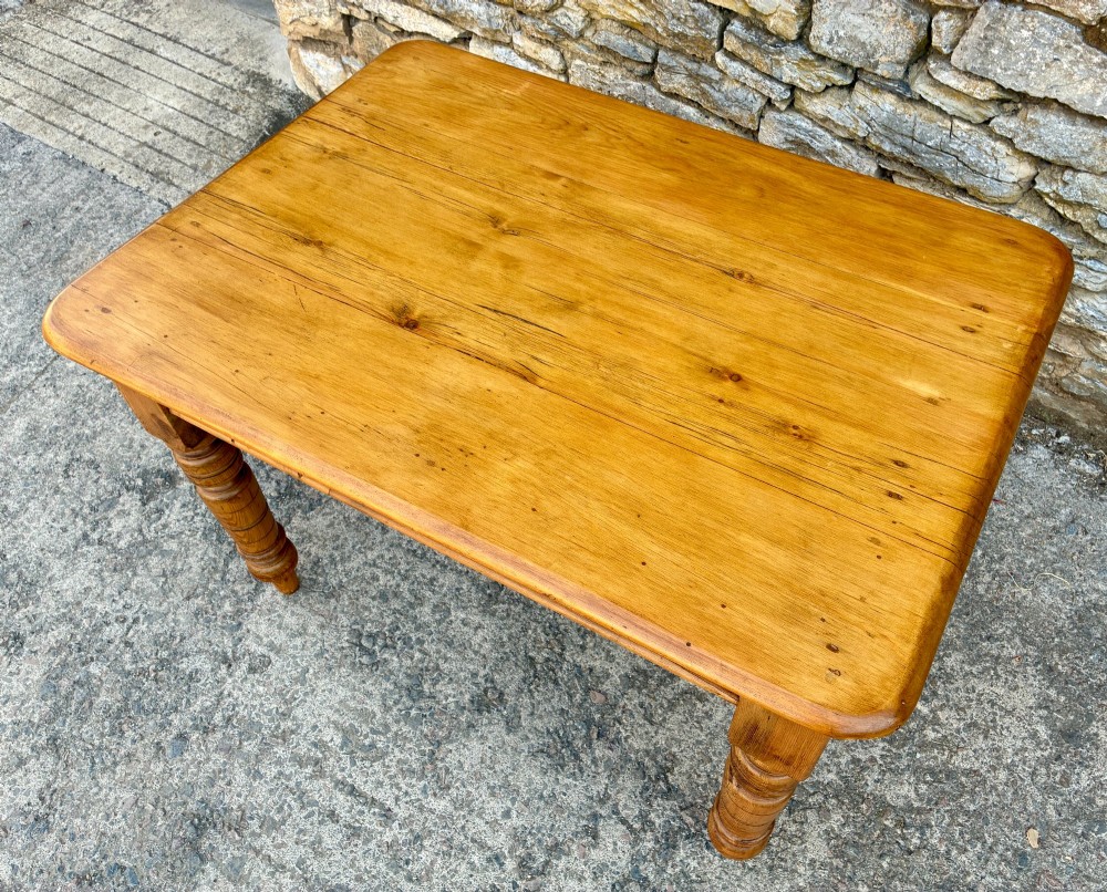 An antique pine farmhouse table featuring turned legs, a frieze drawer with a wooden knob, and a warm timber finish. View IX