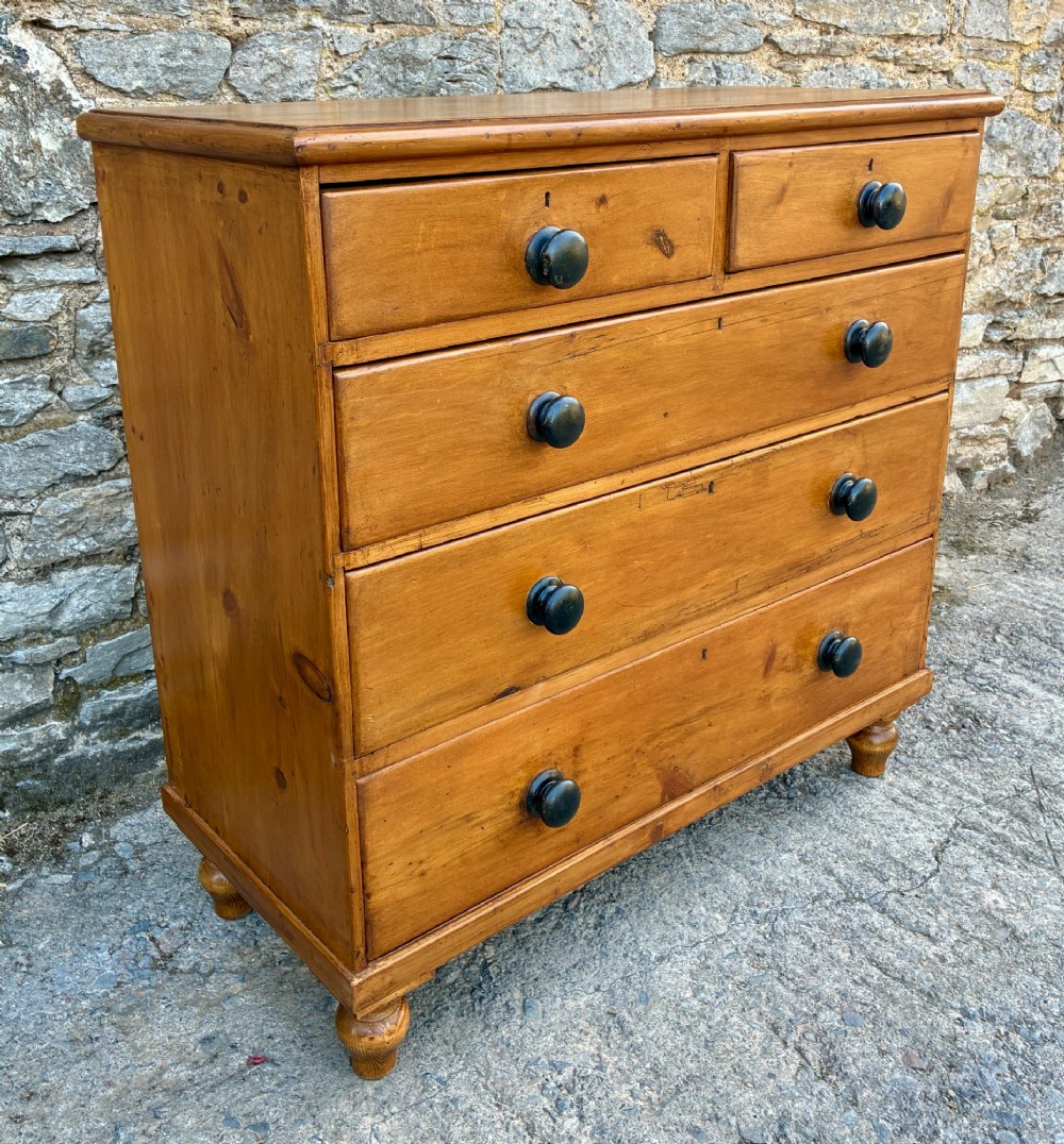 An antique warm pine chest of drawers featuring a two-over-three drawer arrangement with dark turned wooden knobs. View II