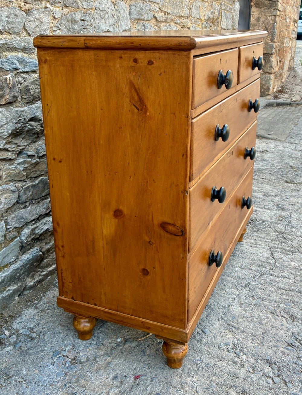 An antique warm pine chest of drawers featuring a two-over-three drawer arrangement with dark turned wooden knobs. View III
