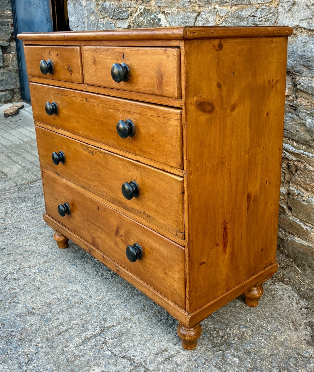 An antique warm pine chest of drawers featuring a two-over-three drawer arrangement with dark turned wooden knobs. View V