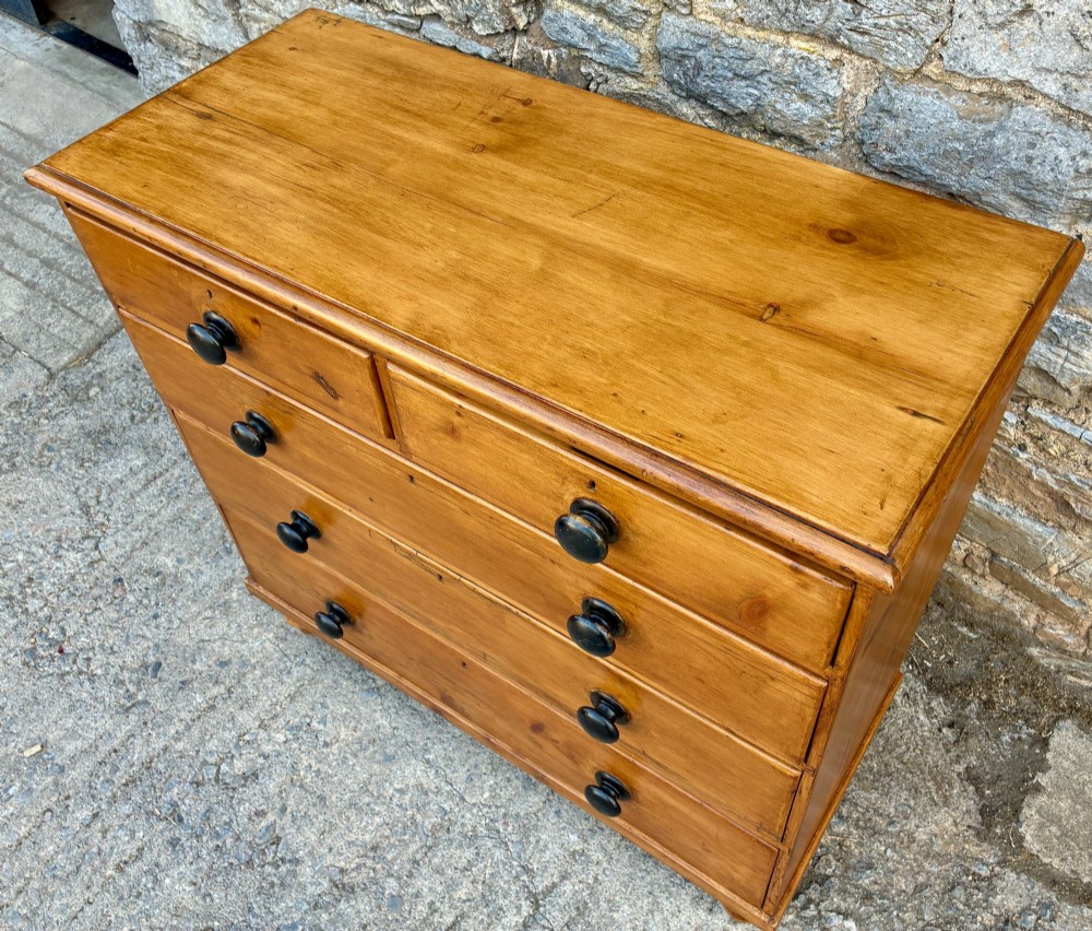 An antique warm pine chest of drawers featuring a two-over-three drawer arrangement with dark turned wooden knobs. View VII