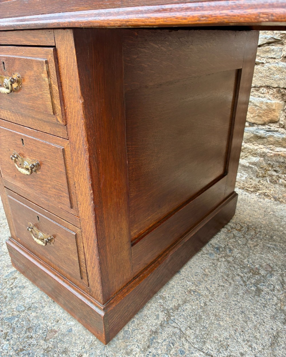 An Edwardian oak pedestal desk featuring a green leather writing surface, nine drawers with brass handles, and twin pedestals on plinth bases. View XII
