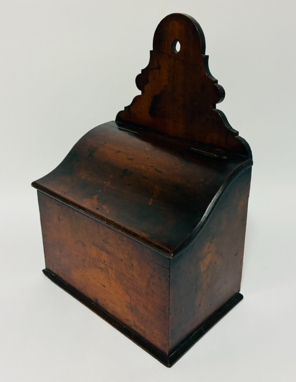 A dark mahogany Georgian hanging salt box with a curved hinged lid and a shaped backplate featuring a circular hanging hole. View II