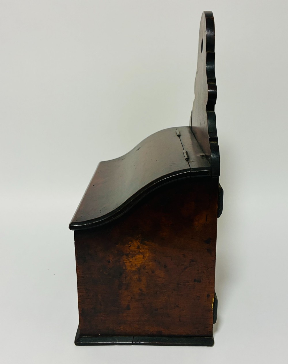 A dark mahogany Georgian hanging salt box with a curved hinged lid and a shaped backplate featuring a circular hanging hole. View VI