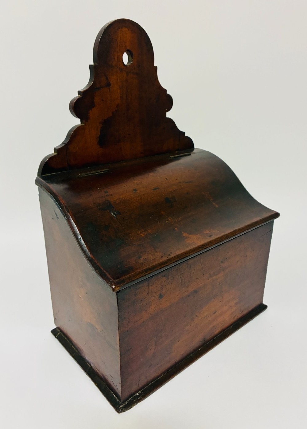 A dark mahogany Georgian hanging salt box with a curved hinged lid and a shaped backplate featuring a circular hanging hole. View X