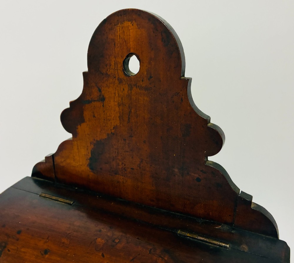A dark mahogany Georgian hanging salt box with a curved hinged lid and a shaped backplate featuring a circular hanging hole. View XII