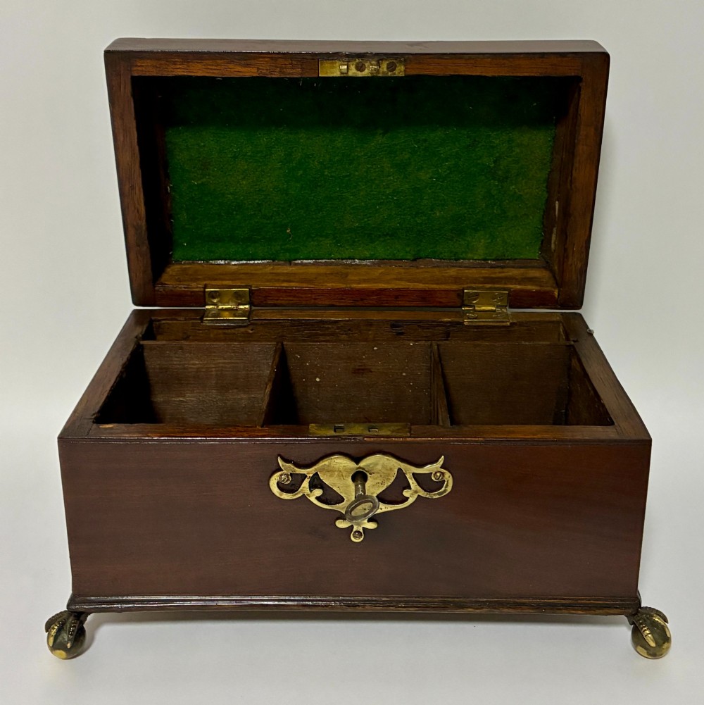 A rectangular George III mahogany tea caddy with a stepped lid, top brass swing handle, pierced brass escutcheon with key, and four brass claw-and-ball feet. View II