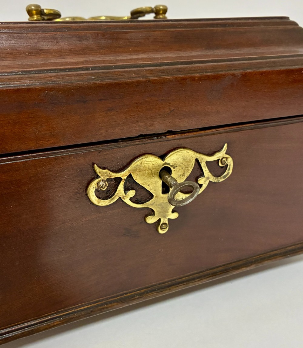 A rectangular George III mahogany tea caddy with a stepped lid, top brass swing handle, pierced brass escutcheon with key, and four brass claw-and-ball feet. View V