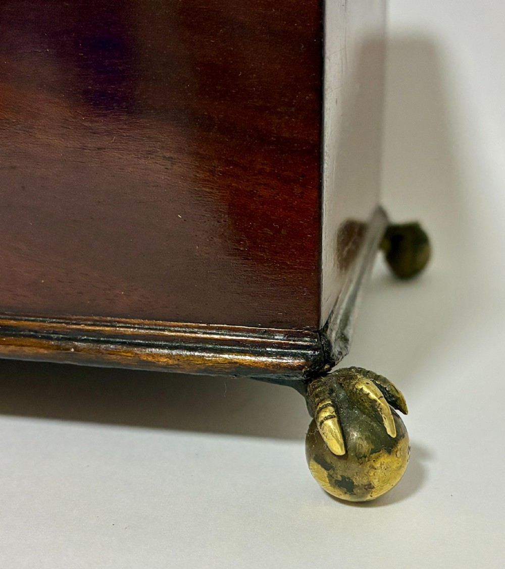 A rectangular George III mahogany tea caddy with a stepped lid, top brass swing handle, pierced brass escutcheon with key, and four brass claw-and-ball feet. View VII