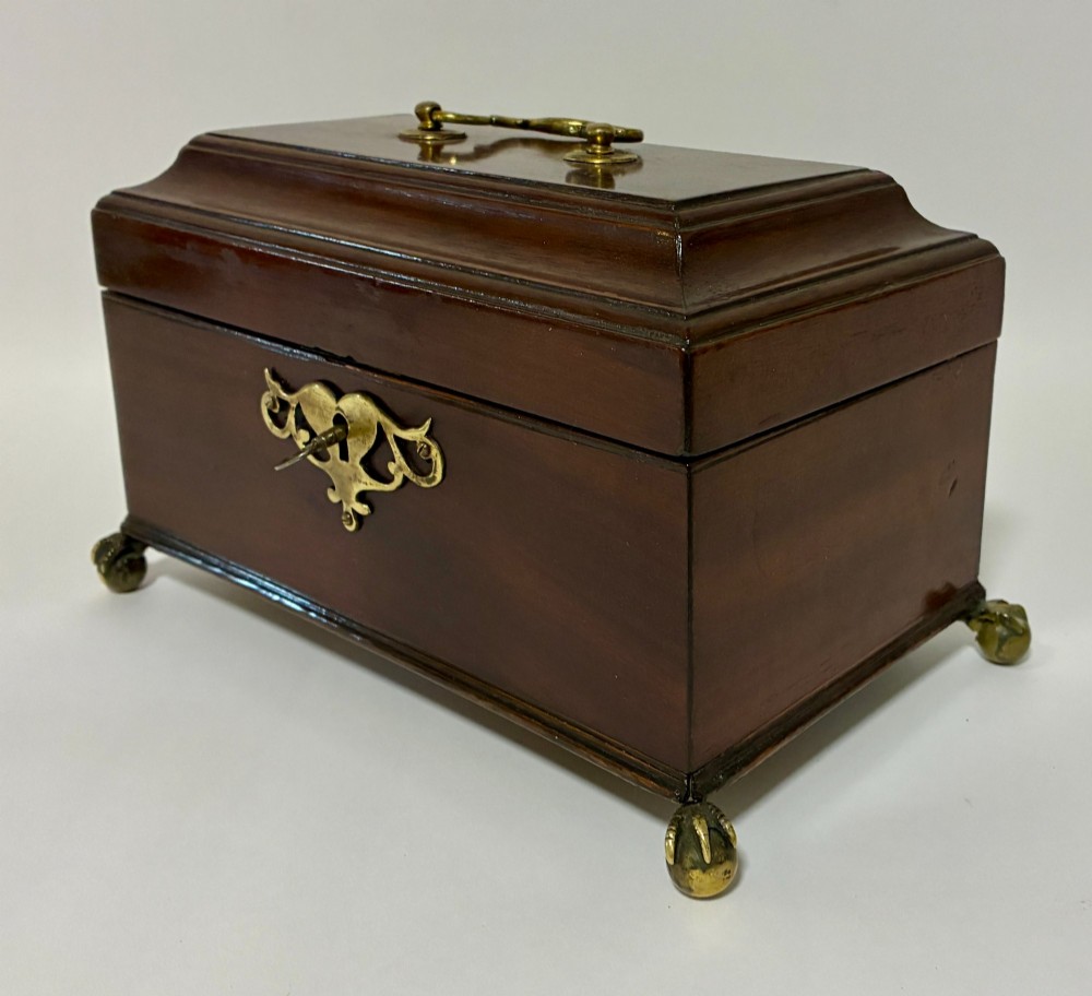 A rectangular George III mahogany tea caddy with a stepped lid, top brass swing handle, pierced brass escutcheon with key, and four brass claw-and-ball feet. View VIII