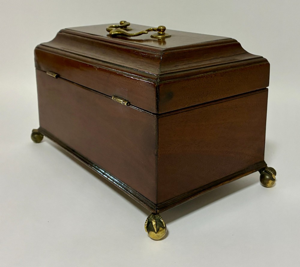 A rectangular George III mahogany tea caddy with a stepped lid, top brass swing handle, pierced brass escutcheon with key, and four brass claw-and-ball feet. View XII
