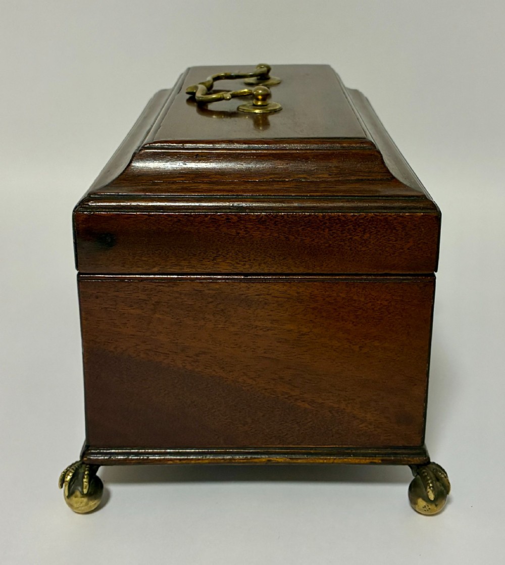 A rectangular George III mahogany tea caddy with a stepped lid, top brass swing handle, pierced brass escutcheon with key, and four brass claw-and-ball feet. View XIII