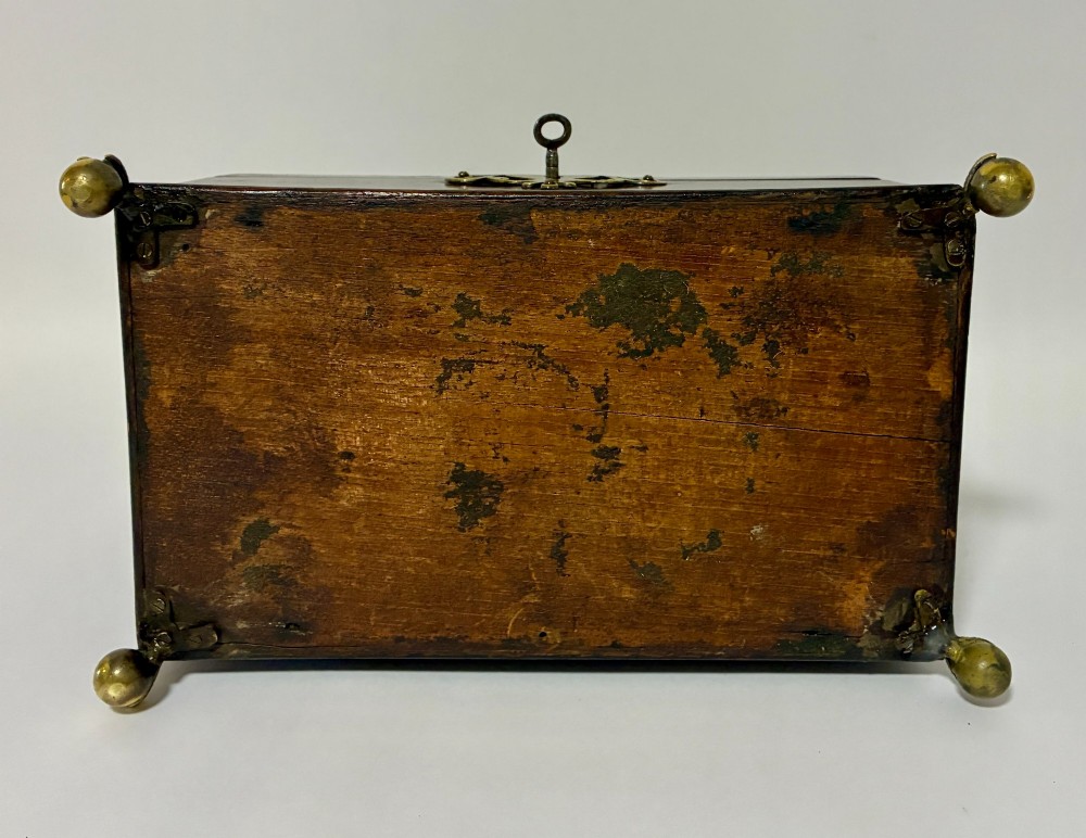 A rectangular George III mahogany tea caddy with a stepped lid, top brass swing handle, pierced brass escutcheon with key, and four brass claw-and-ball feet. View XIV