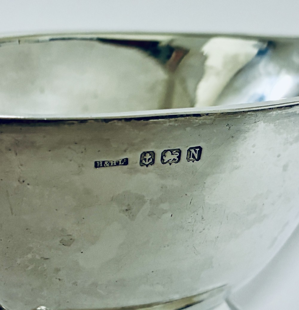 An Art Deco sterling silver sauce boat featuring an angular handle, stepped pedestal base, and clear English hallmarks on the side. View VI