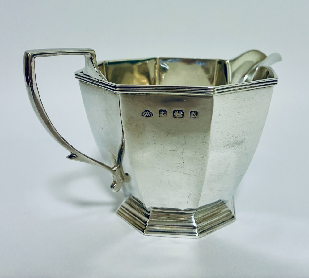 An octagonal sterling silver milk jug featuring an angular handle, a pronounced pouring spout, and visible stamped hallmarks on the front facet. View II