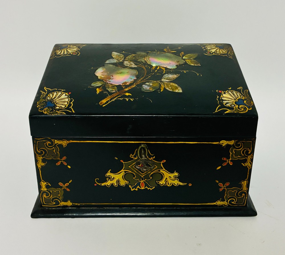 A black lacquered Victorian papier-mache stationery box featuring mother-of-pearl flower inlays on the lid and gilded corner scrollwork around a central brass keyhole.