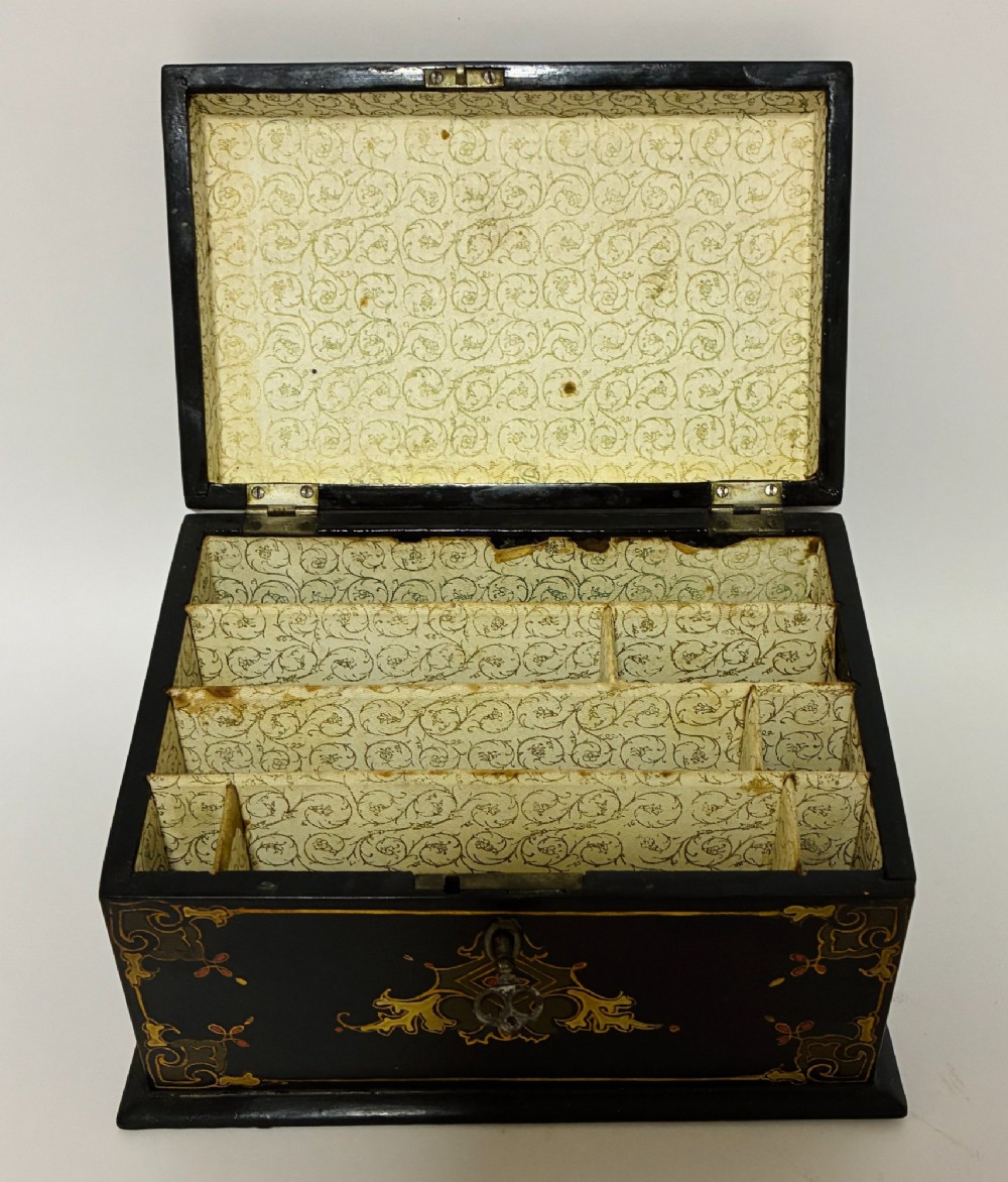 A black lacquered Victorian papier-mache stationery box featuring mother-of-pearl flower inlays on the lid and gilded corner scrollwork around a central brass keyhole. View II