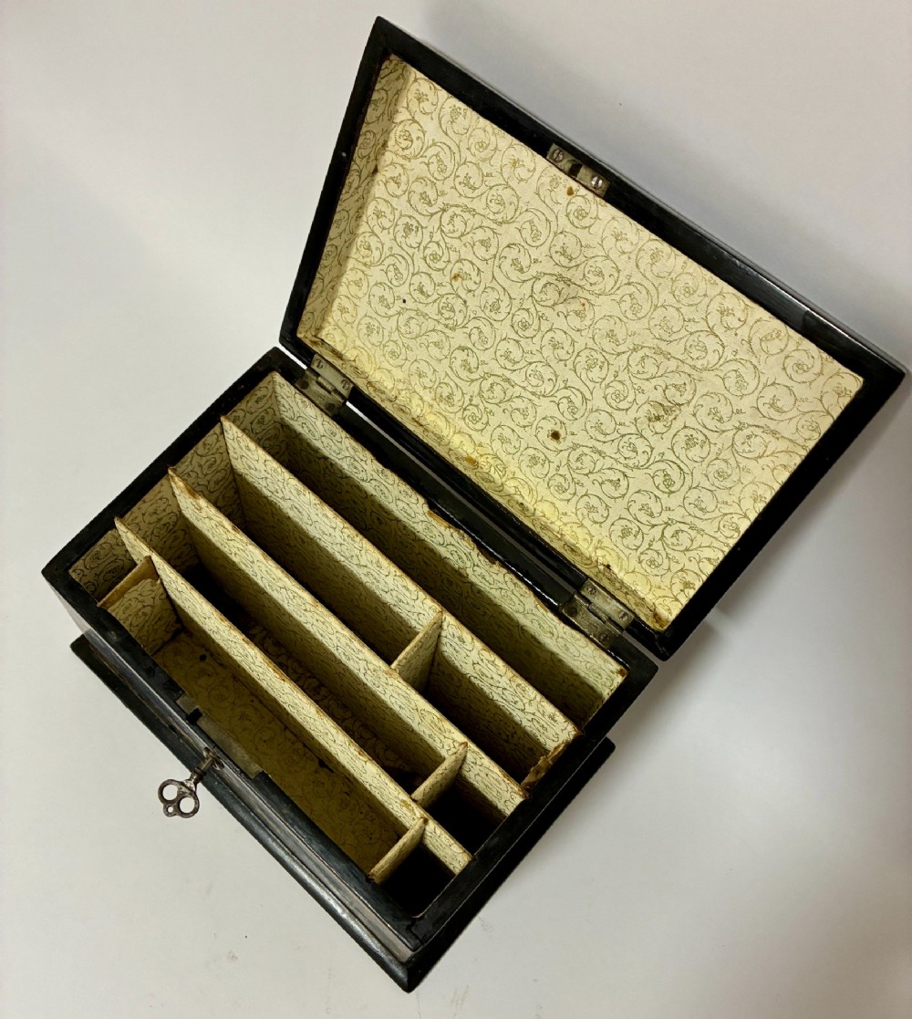 A black lacquered Victorian papier-mache stationery box featuring mother-of-pearl flower inlays on the lid and gilded corner scrollwork around a central brass keyhole. View III