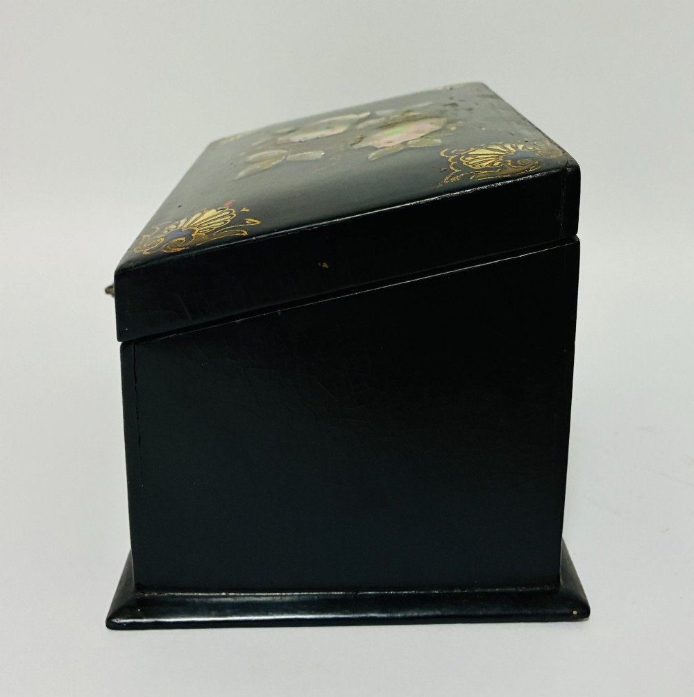 A black lacquered Victorian papier-mache stationery box featuring mother-of-pearl flower inlays on the lid and gilded corner scrollwork around a central brass keyhole. View VI
