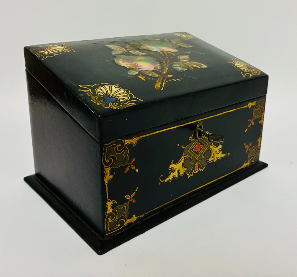 A black lacquered Victorian papier-mache stationery box featuring mother-of-pearl flower inlays on the lid and gilded corner scrollwork around a central brass keyhole. View IX