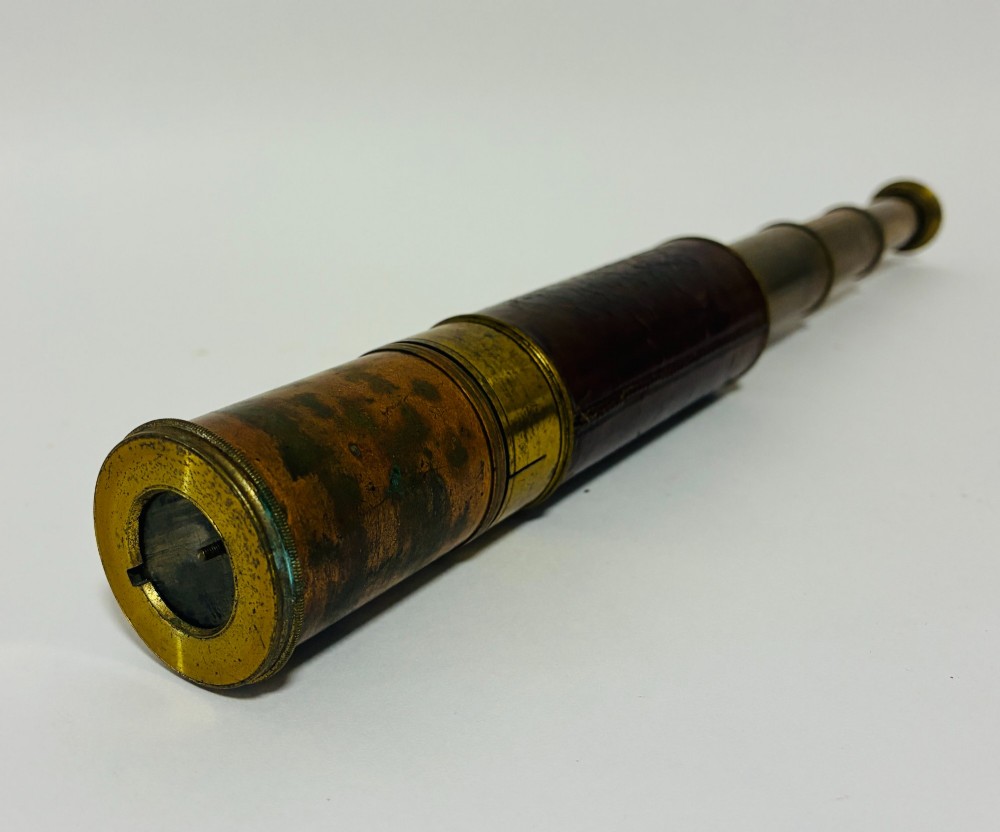 An extended three-draw antique brass pocket telescope featuring a dark brown textured leather barrel wrap. View III