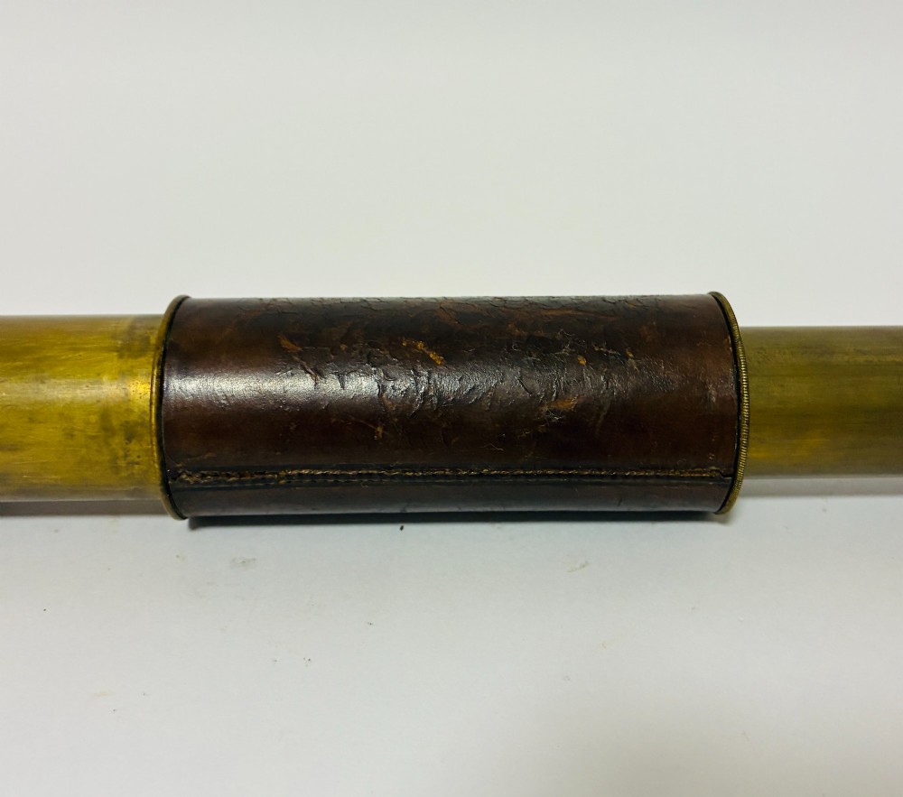 An extended three-draw antique brass pocket telescope featuring a dark brown textured leather barrel wrap. View V