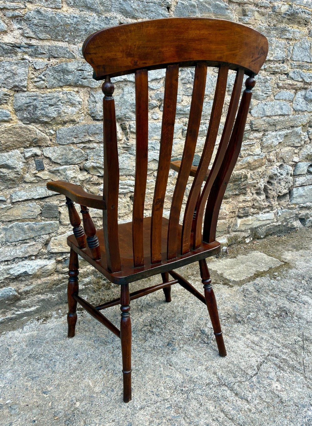 A Victorian country lath back armchair in warm brown wood, featuring vertical back slats, curved armrests, a contoured seat, and turned legs. View VI