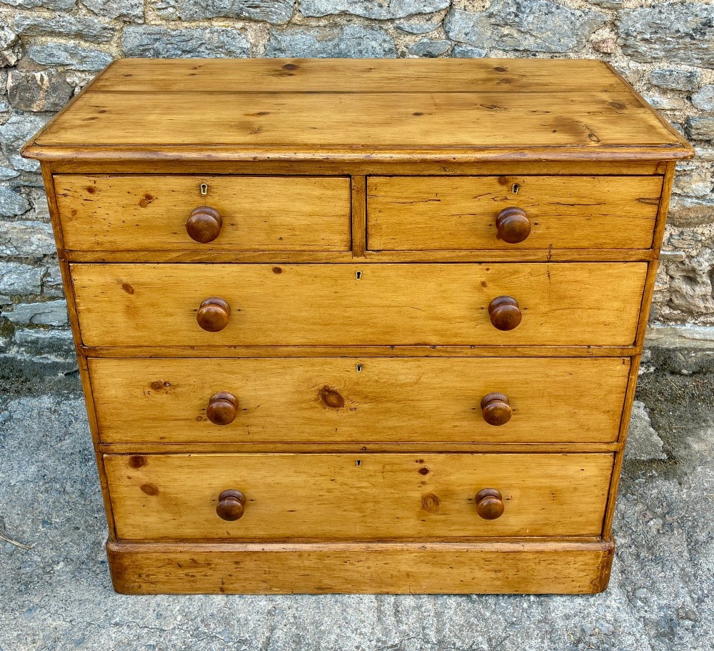 A Victorian pine chest of drawers featuring a two short over three long drawer arrangement with turned wooden knobs.