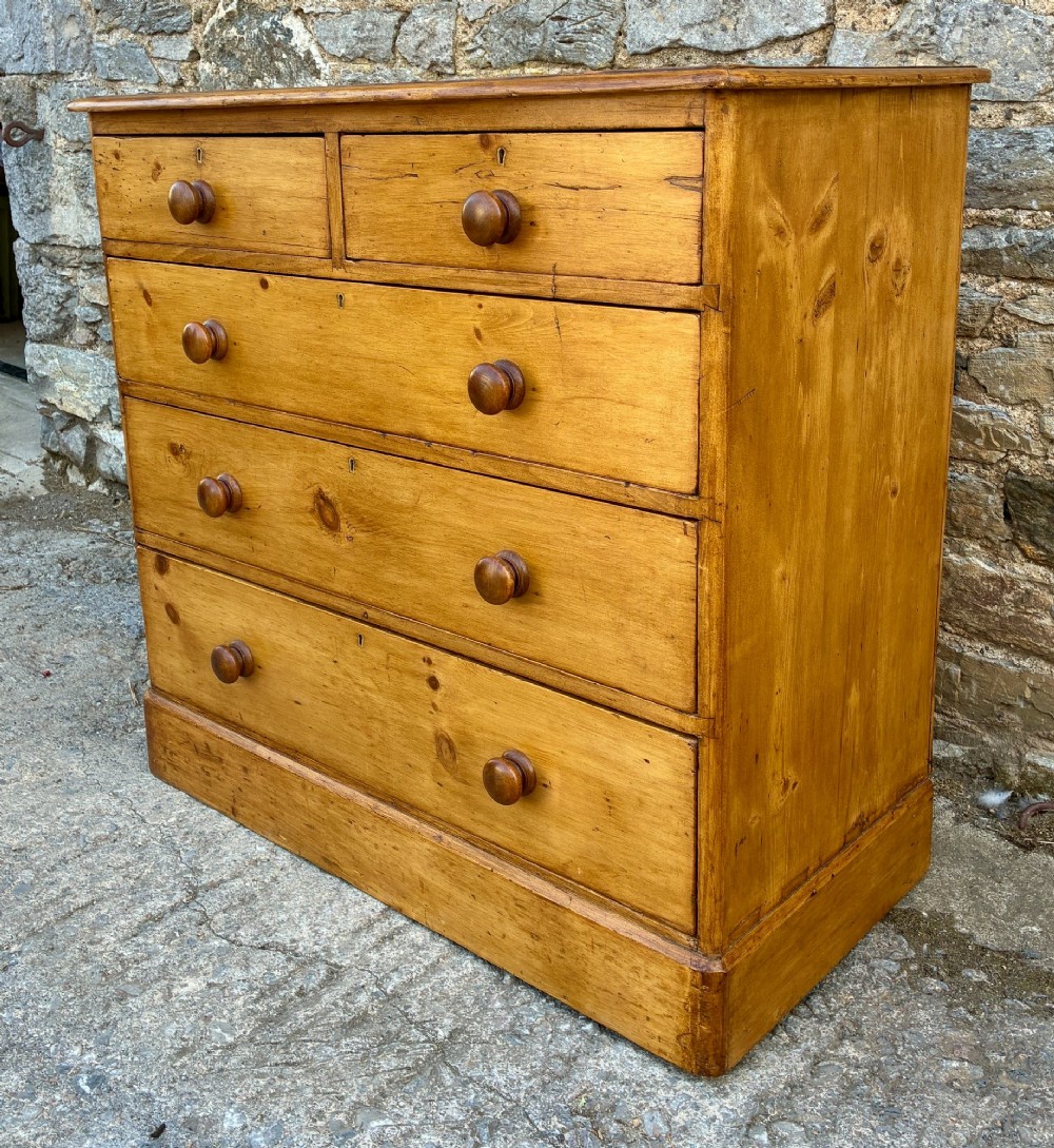 A Victorian pine chest of drawers featuring a two short over three long drawer arrangement with turned wooden knobs. View V