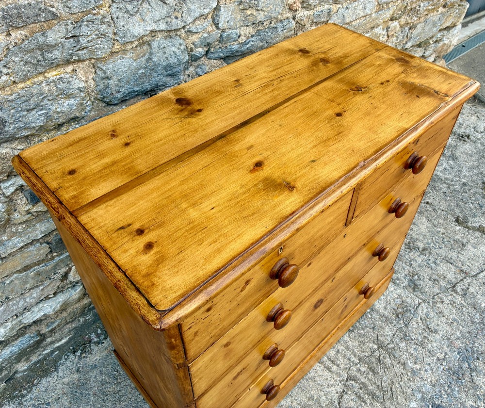 A Victorian pine chest of drawers featuring a two short over three long drawer arrangement with turned wooden knobs. View VIII