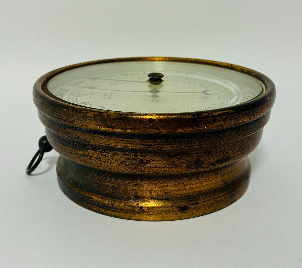 A circular antique brass wall barometer with a cream dial displaying weather conditions and an integrated glass tube thermometer. View III