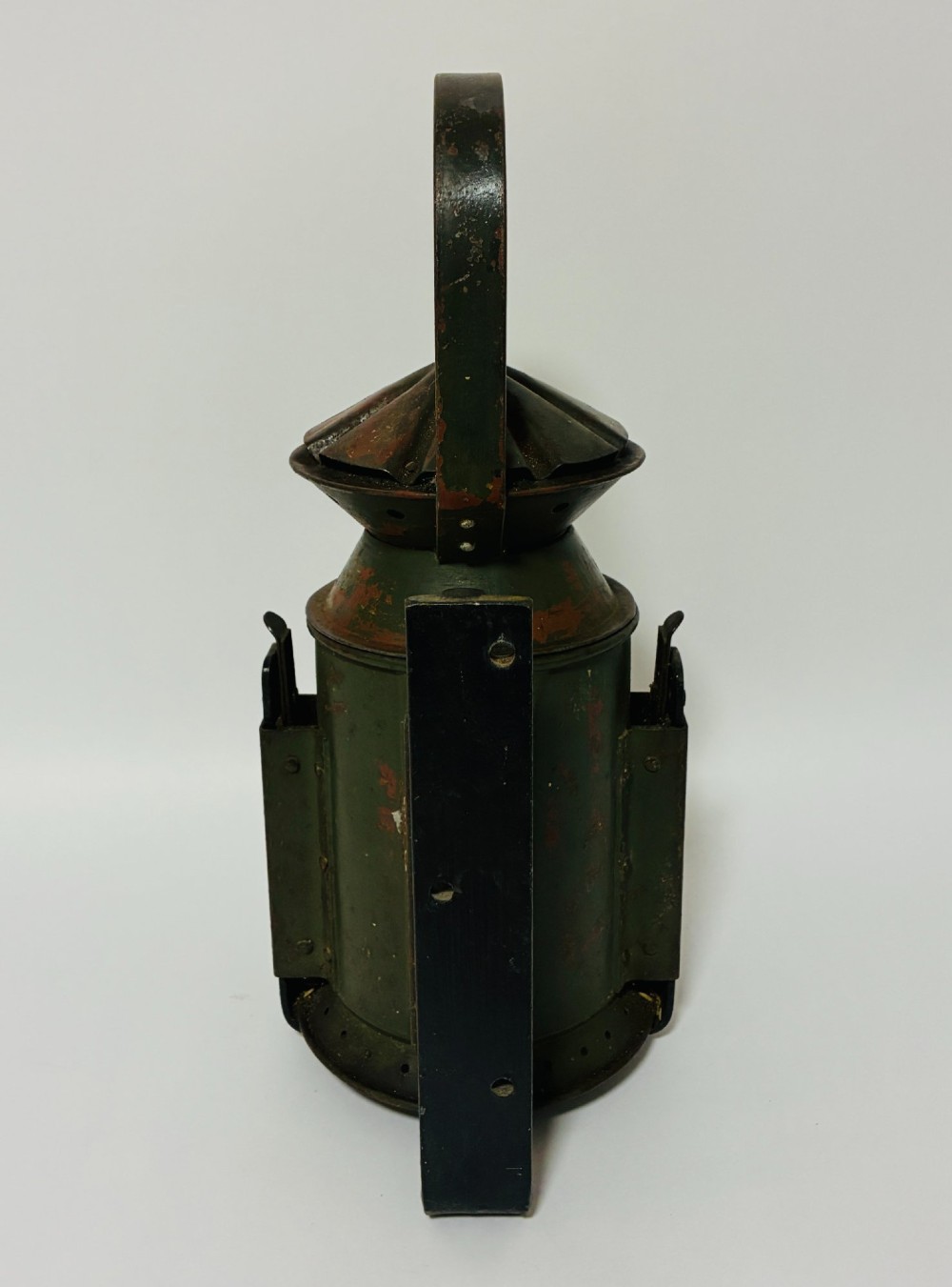 A vintage olive green painted metal railway signal lamp featuring a large round glass lens with a brass rim and a tall arched carrying handle. View III