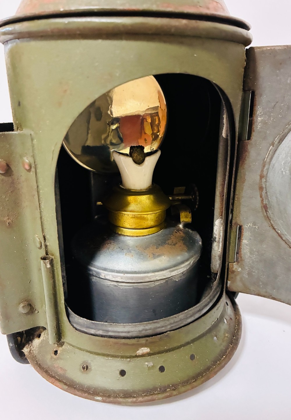 A vintage olive green painted metal railway signal lamp featuring a large round glass lens with a brass rim and a tall arched carrying handle. View IX