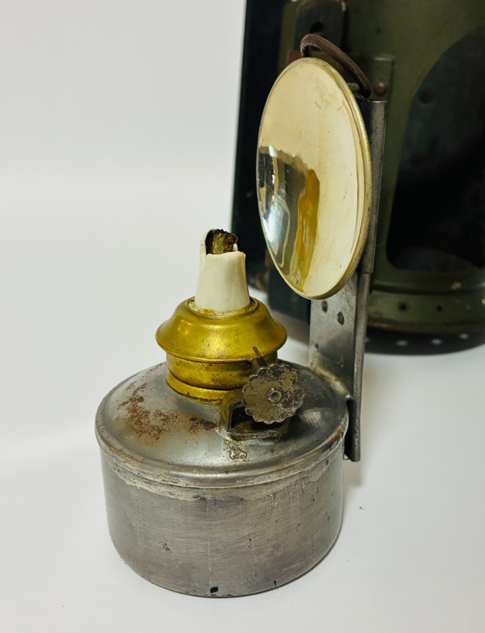 A vintage olive green painted metal railway signal lamp featuring a large round glass lens with a brass rim and a tall arched carrying handle. View XIII