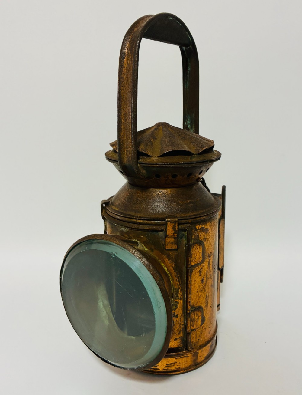 An antique metal railway signalling lamp with an arched top carrying handle, a conical vented cap, and a prominent circular glass lens. View VII
