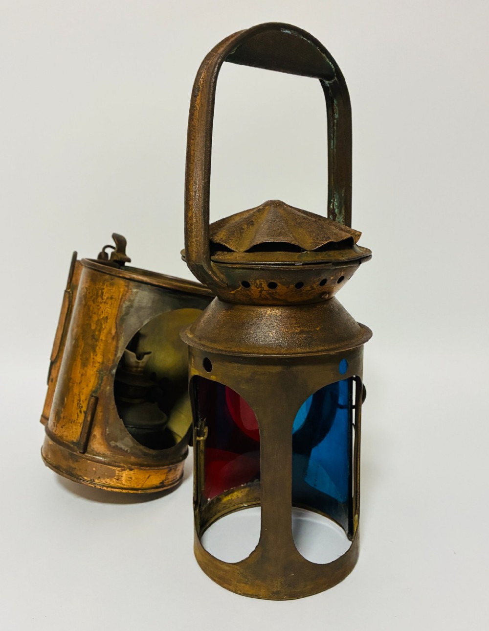 An antique metal railway signalling lamp with an arched top carrying handle, a conical vented cap, and a prominent circular glass lens. View X