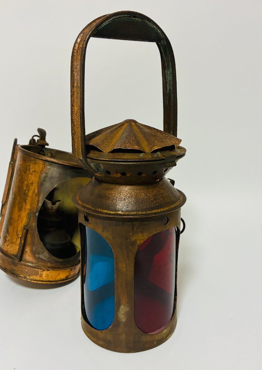 An antique metal railway signalling lamp with an arched top carrying handle, a conical vented cap, and a prominent circular glass lens. View XI