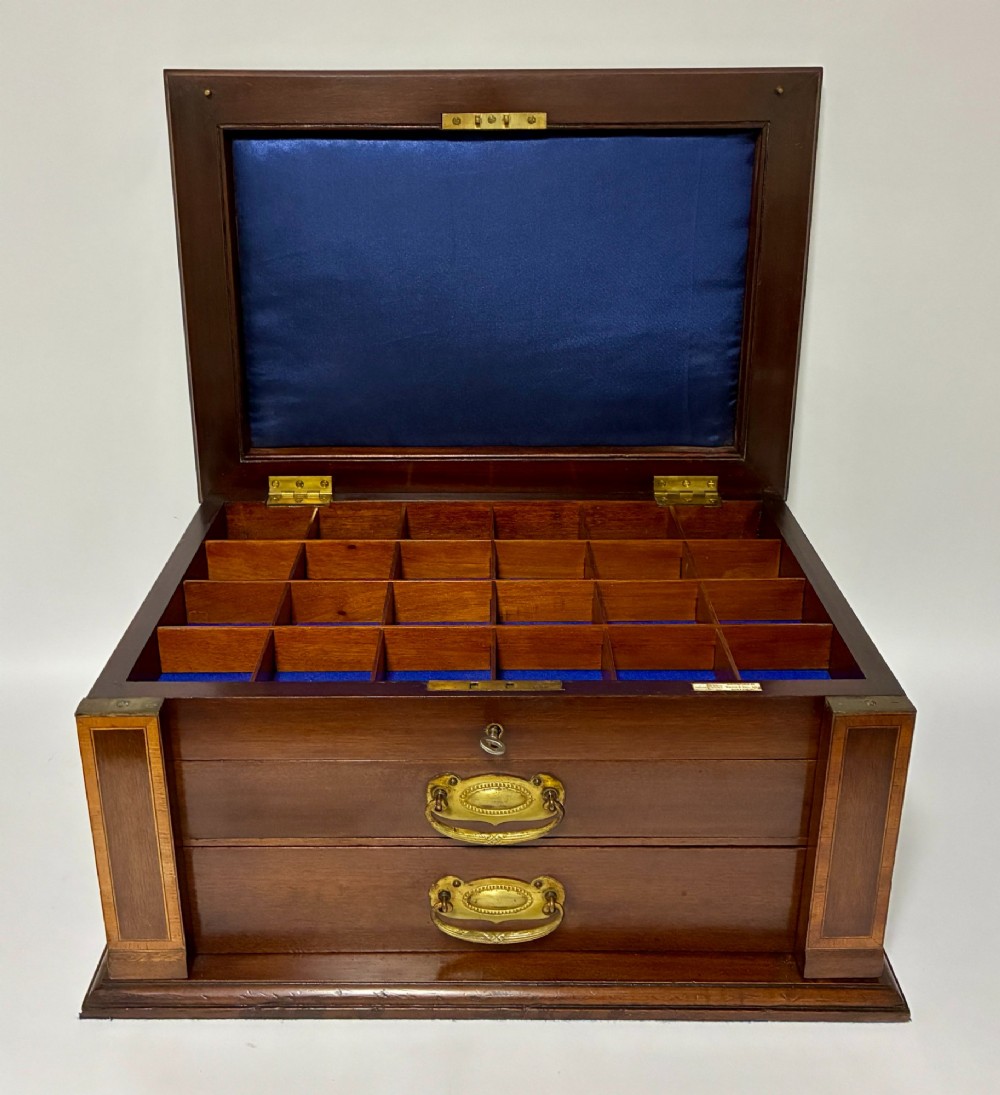 An Edwardian warm brown mahogany collectors box featuring wood inlay, brass drop handles, and a polished lid. View II