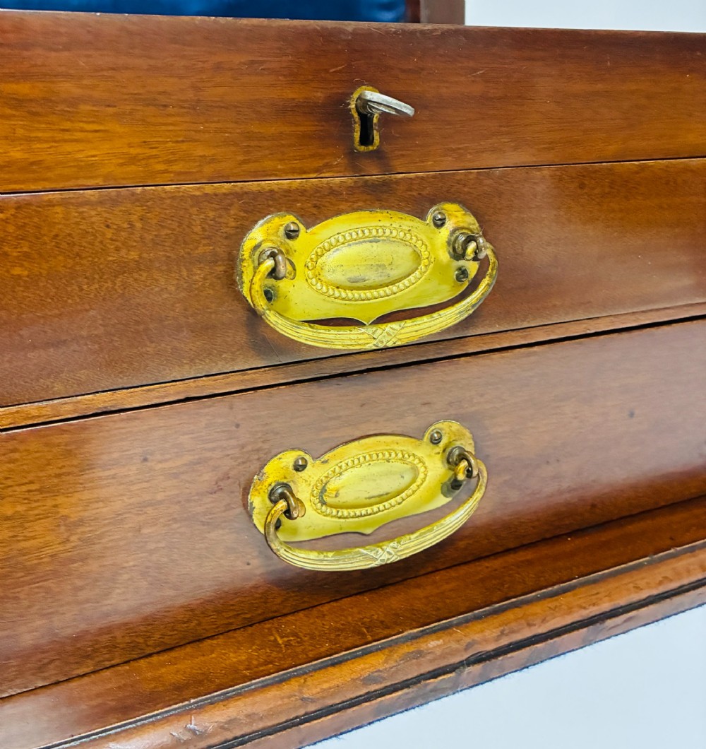 An Edwardian warm brown mahogany collectors box featuring wood inlay, brass drop handles, and a polished lid. View VI