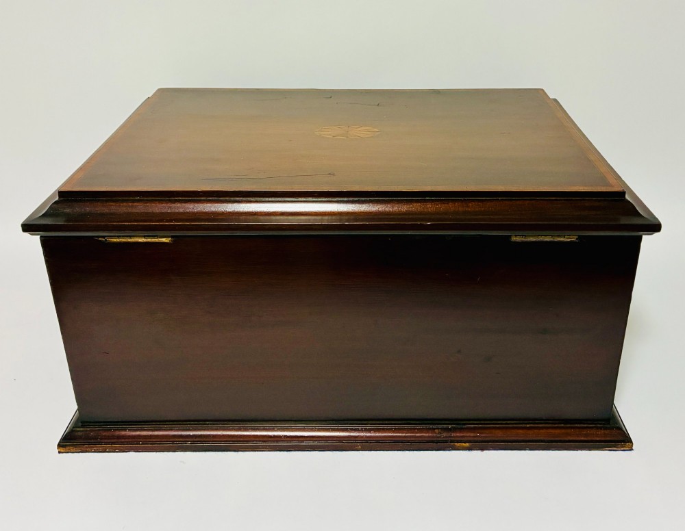 An Edwardian warm brown mahogany collectors box featuring wood inlay, brass drop handles, and a polished lid. View X