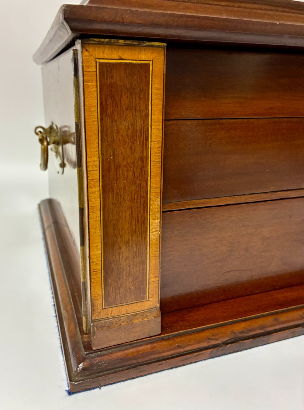 An Edwardian warm brown mahogany collectors box featuring wood inlay, brass drop handles, and a polished lid. View XIV