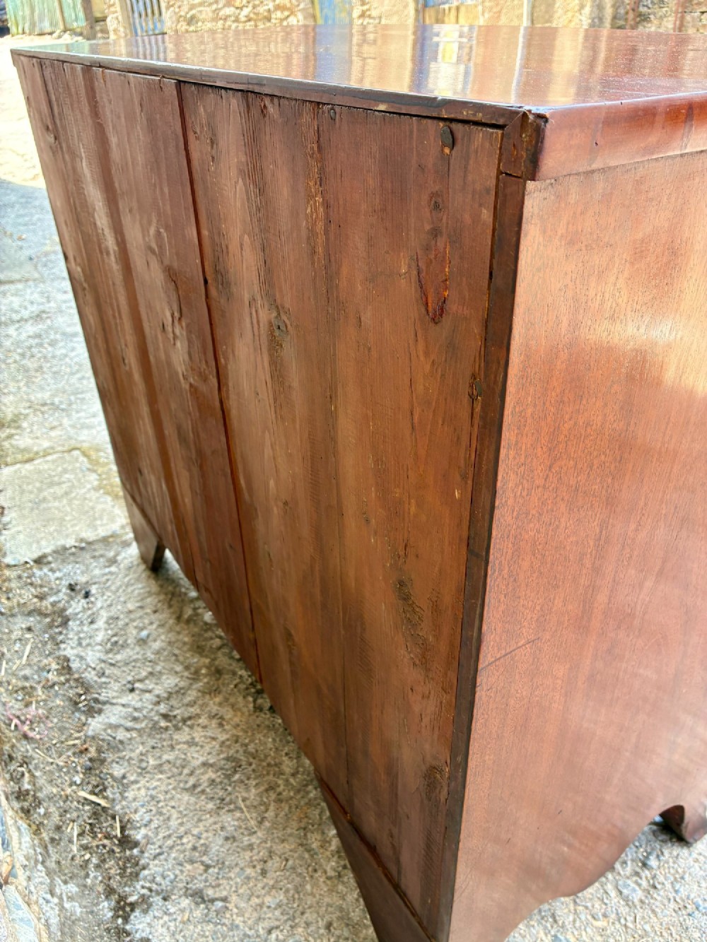 An antique Regency mahogany chest of drawers featuring a curved bowfront shape, three drawers with oval brass handles, and splayed bracket feet. View XIV