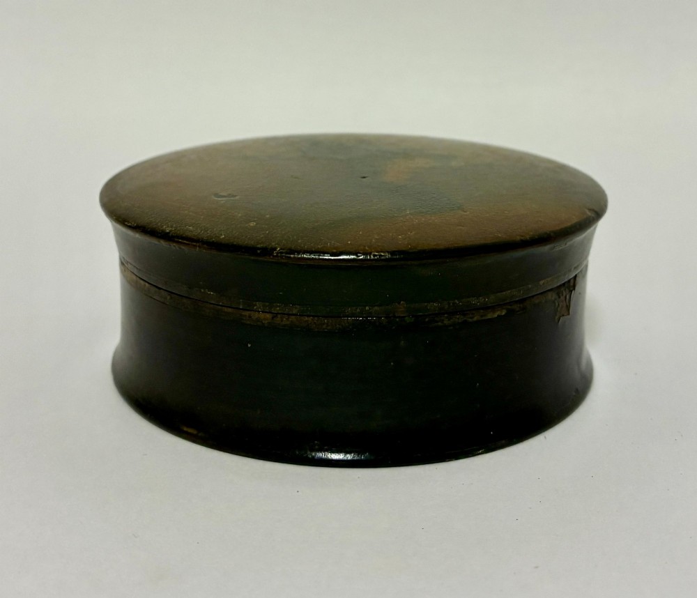 A circular Georgian papier-mache table snuff box featuring a hand-painted depiction of a gentleman in a top hat and tailcoat against a dark lacquered background. View III