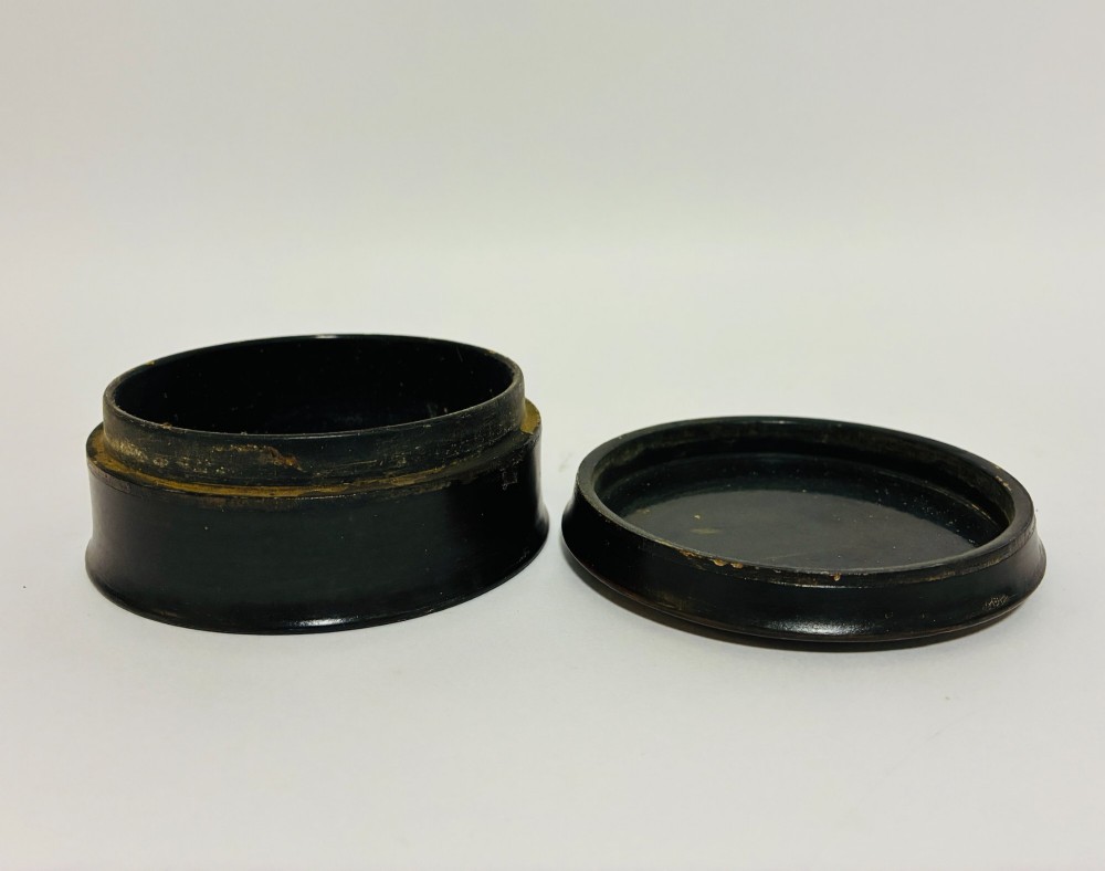 A circular Georgian papier-mache table snuff box featuring a hand-painted depiction of a gentleman in a top hat and tailcoat against a dark lacquered background. View X