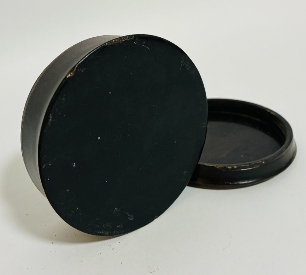 A circular Georgian papier-mache table snuff box featuring a hand-painted depiction of a gentleman in a top hat and tailcoat against a dark lacquered background. View XI